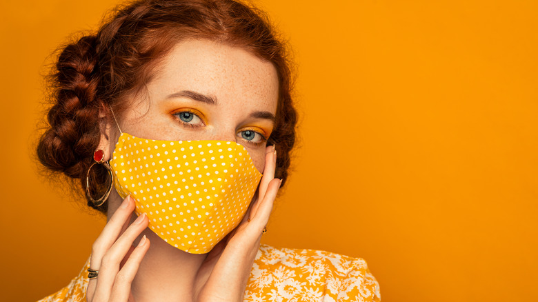 Woman wearing mango eyeshadow and mask, on mango background