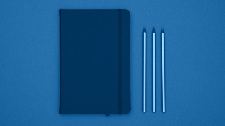 Blue notebook, blue pens on blue background