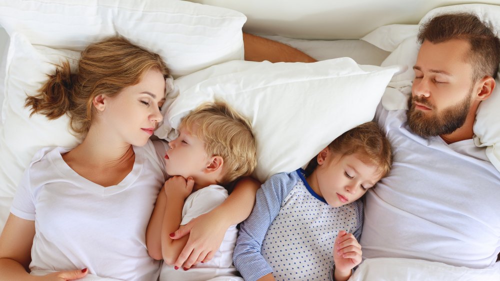 family sleeping in bed together