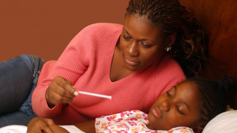 mom with thermometer and sick child