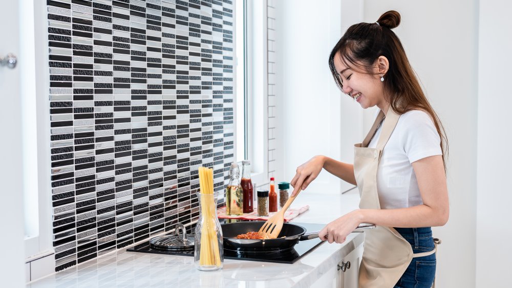 A woman making spaghetti and sauce in her kitchen