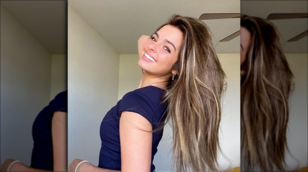 TikTok star Addison Rae smiling in a selfie, touching her hair