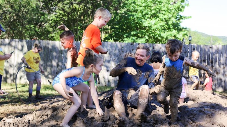 father and kids playing in mud