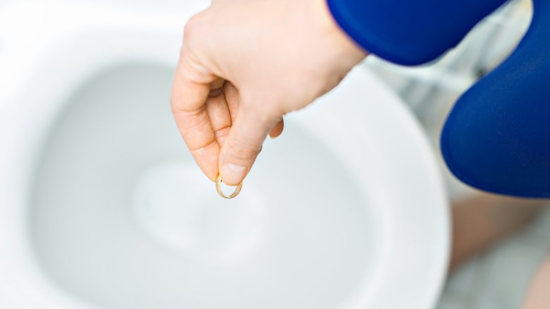 woman throwing wedding ring in toilet