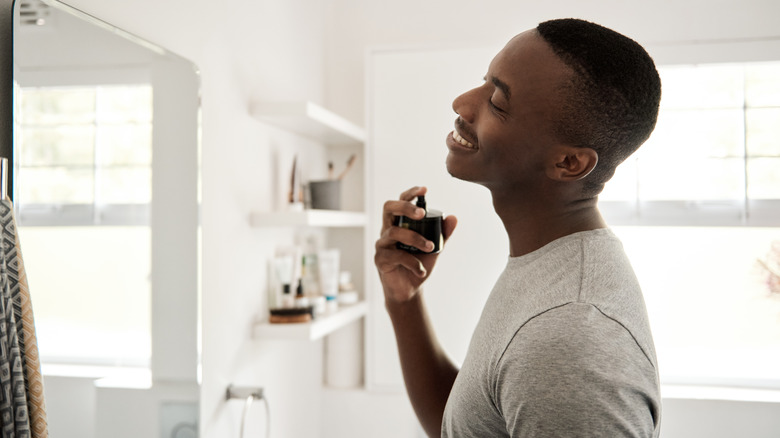 A man spritzes on perfume