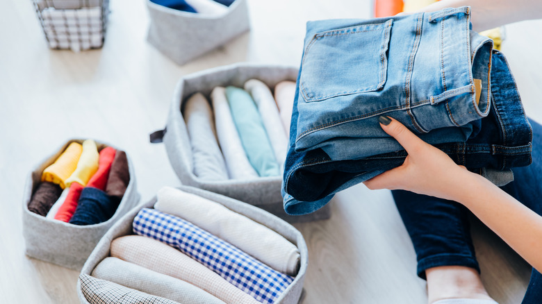 woman putting folded jean in store cubby