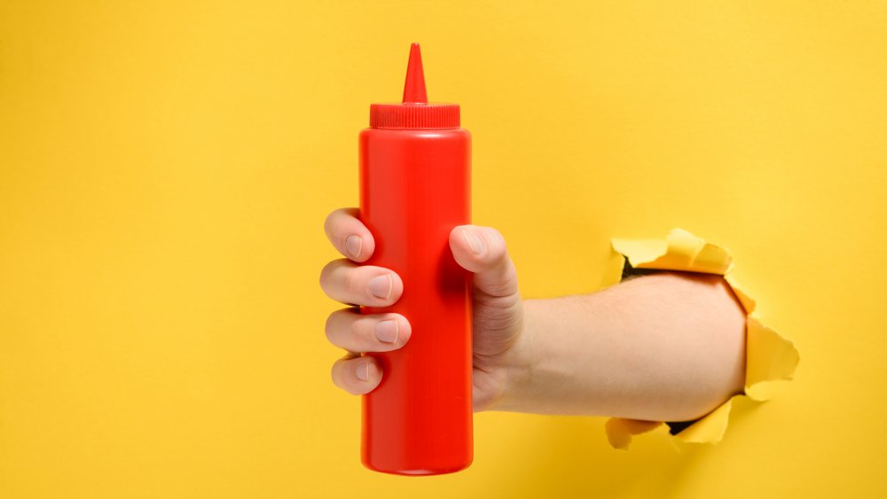 Hand offering a ketchup bottle