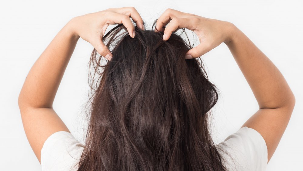 A woman itching her scalp 