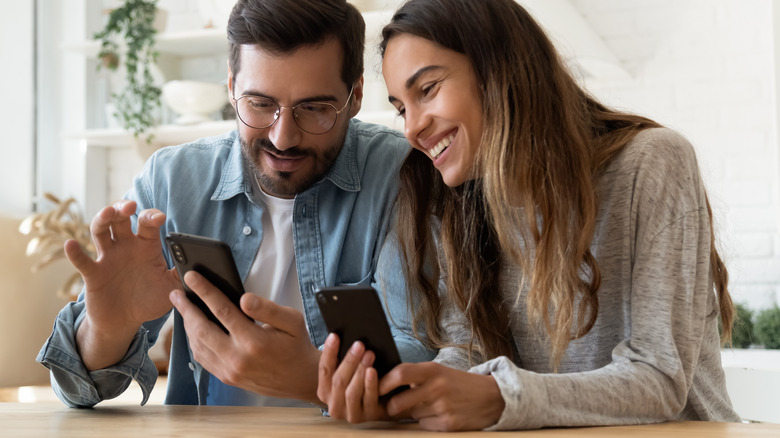 Couple laughing holding phones 