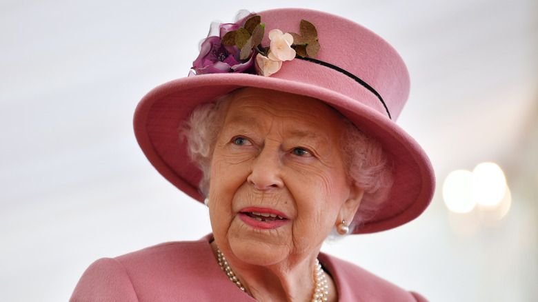 Queen Elizabeth looks at something in a pink outfit