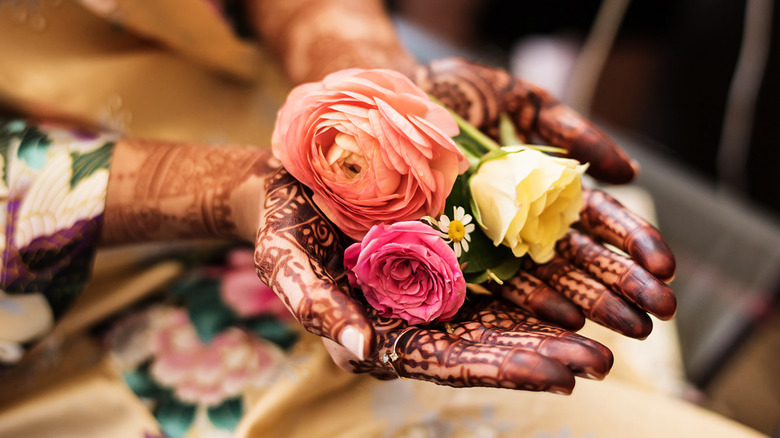 Hands with henna holding flowers