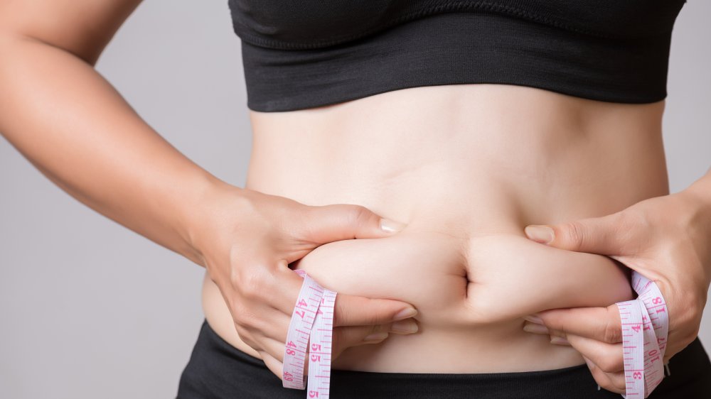 Woman measuring belly fat