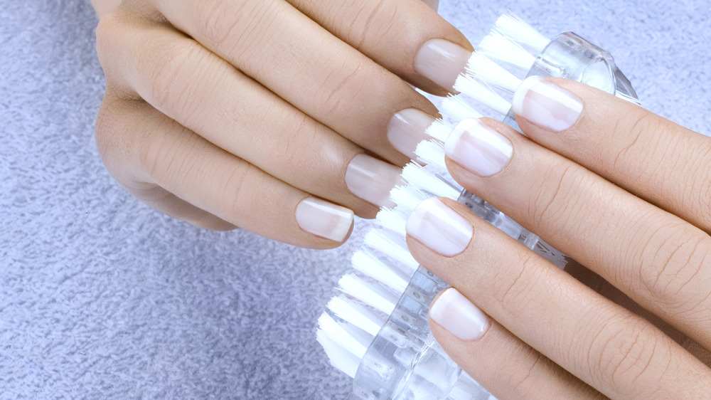 Closeup of woman using a fingernail brush to clean her hands.