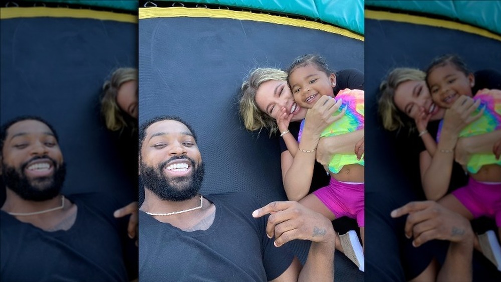 Tristan Thompson, Khloe Kardashian, and their daughter True playing on a trampoline in an Instagram selfie