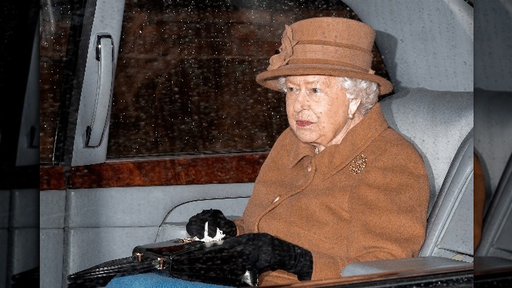 Queen Elizabeth II in a limo with her bag