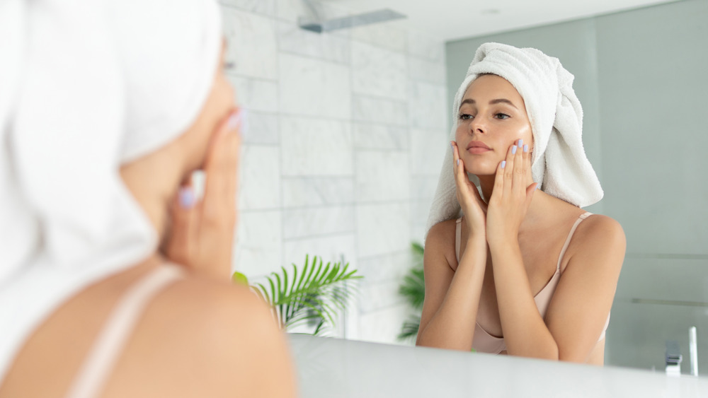 Woman applying face cream in the bathroom