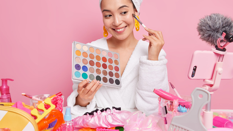 woman applying makeup in front of phone