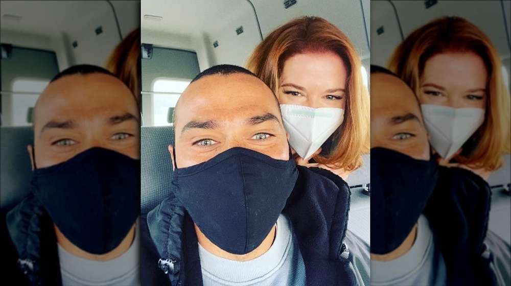 Jesse Williams and Sarah Drew smile with face masks on