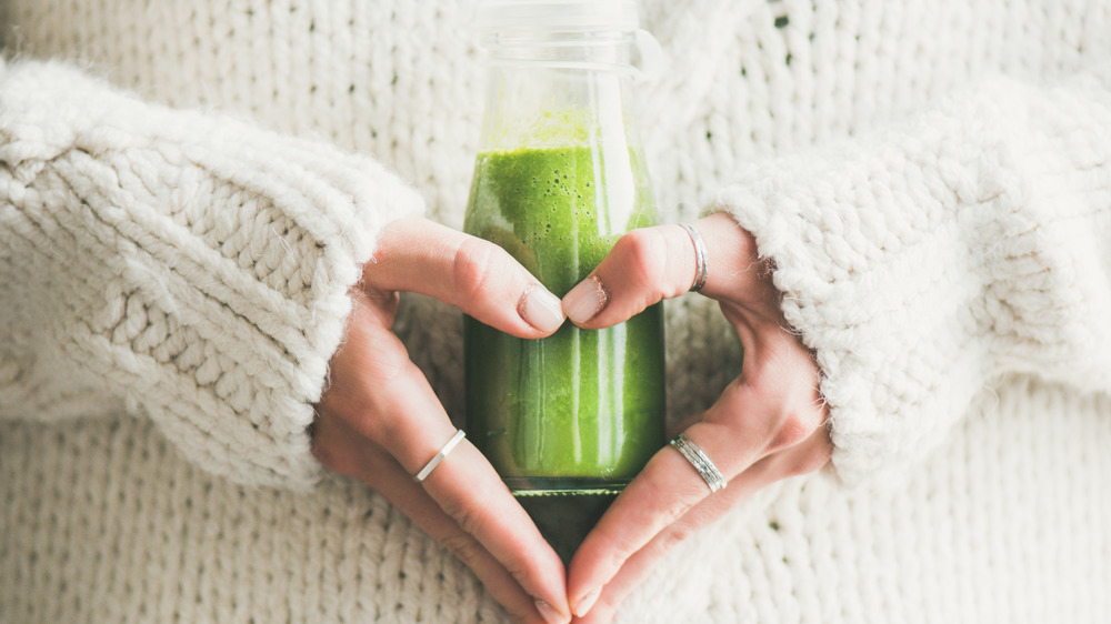 A woman's hands holding a green smoothie