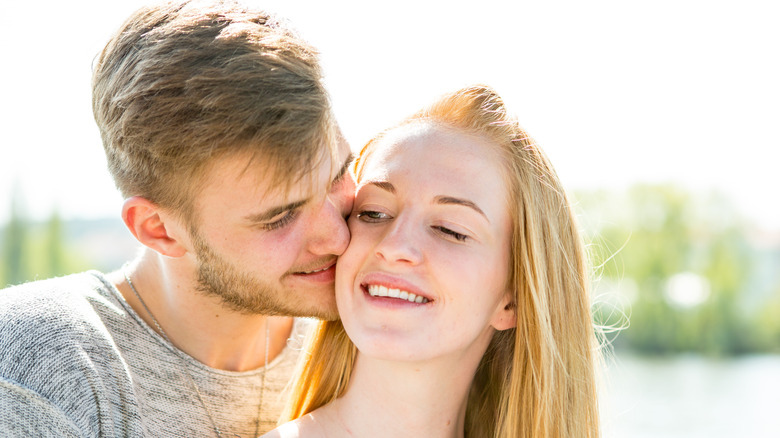 A man kissing a blonde woman