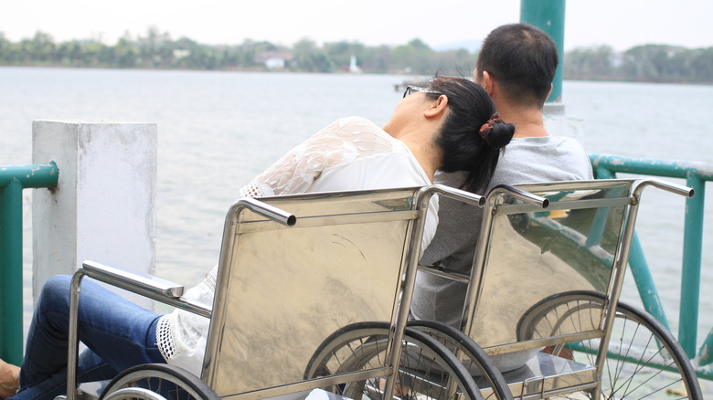 A couple sitting in wheelchairs looking away
