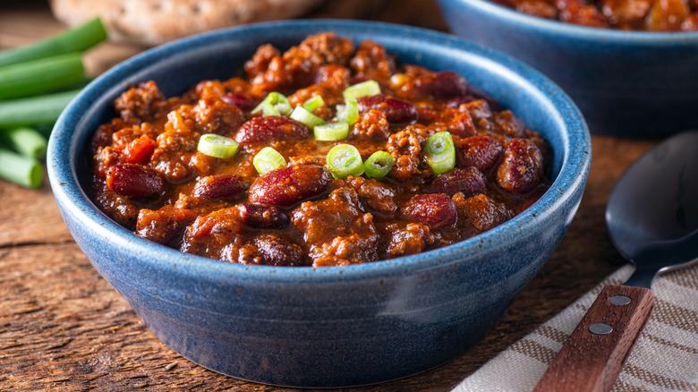 A bowl of chili with scallions