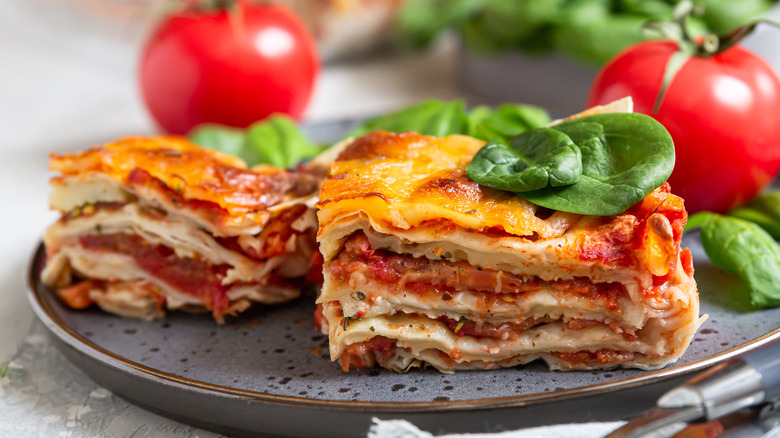 A plate of lasagna with basil and tomatoes