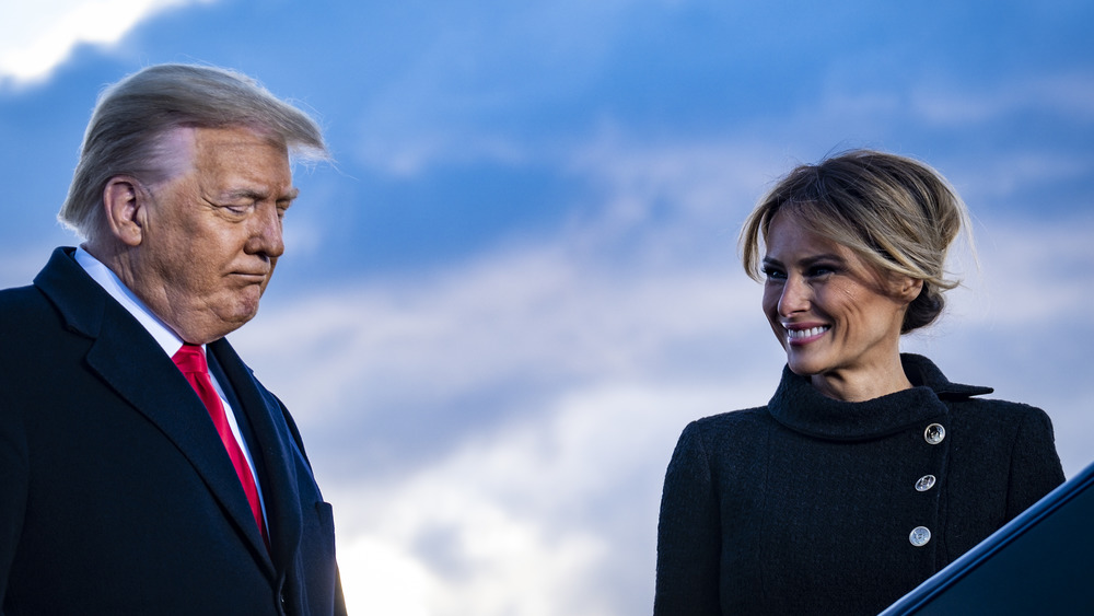 Donald Trump looking down Melania Trump smiling at him with hair up