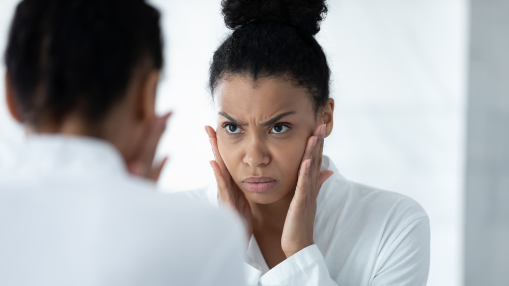 Woman looking in the mirror touching her face