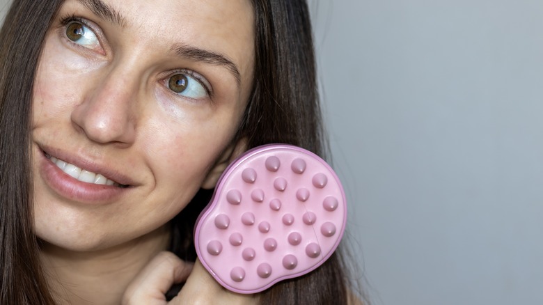 Woman smiling holding scalp massager 