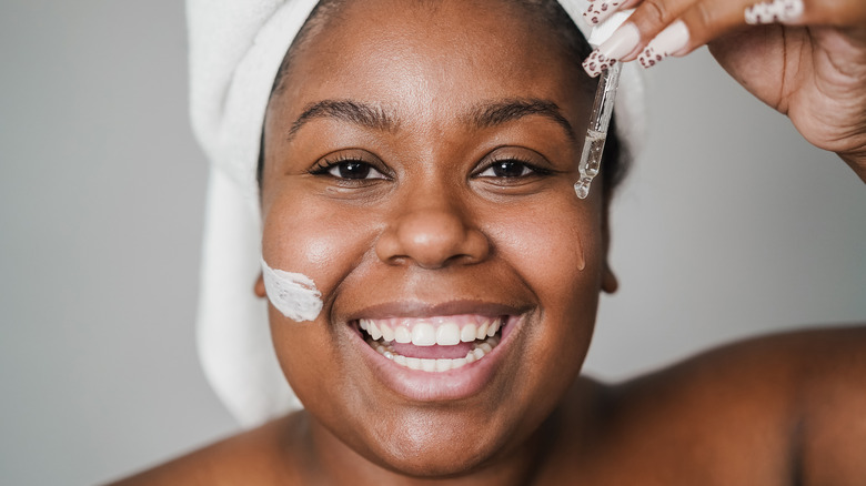 Smiling woman dropping serum on face