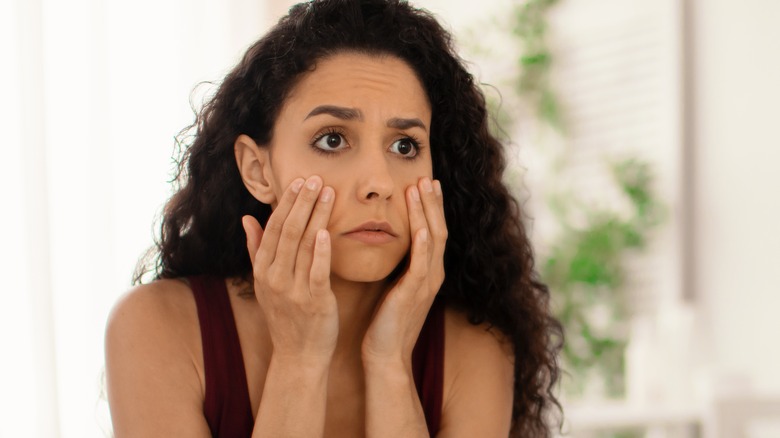 Woman looking concerned in mirror