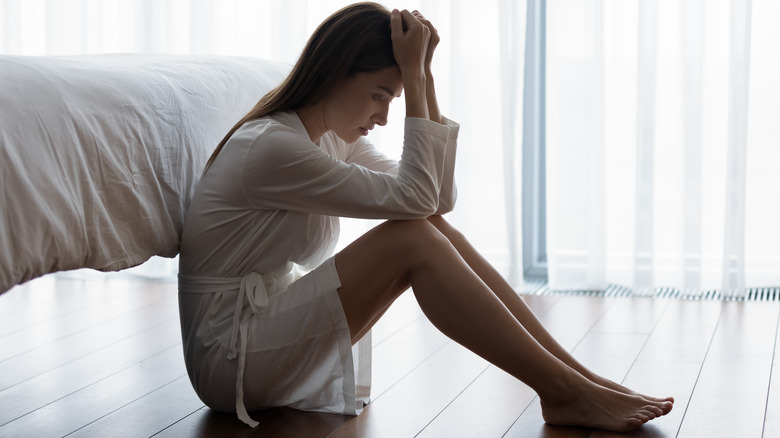 woman sitting on the floor looking depressed