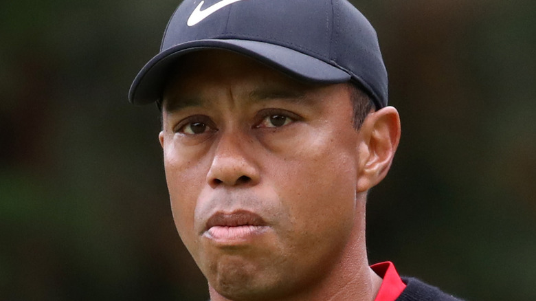 Tiger Woods holds a golf ball while looking mad