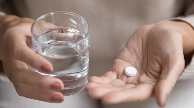 person holding aspirin and glass of water