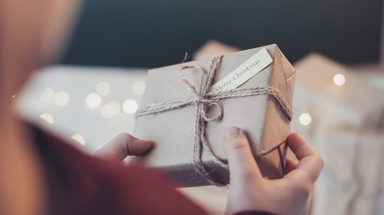 Someone holding a wrapped present that says Merry Christmas