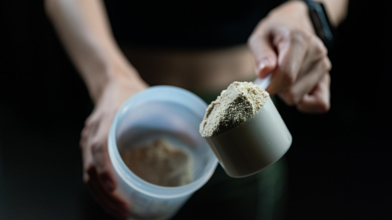 hands scooping protein powder into container