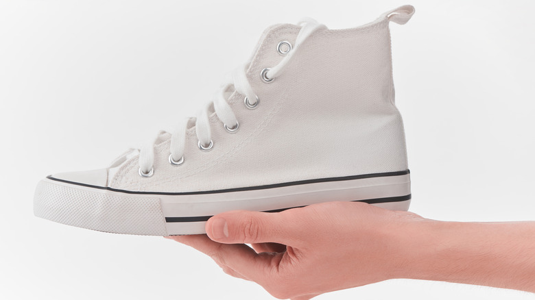 hand holding up clean white canvas sneaker 