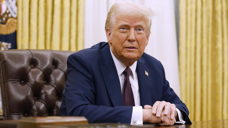 Donald Trump sitting at Oval Office desk