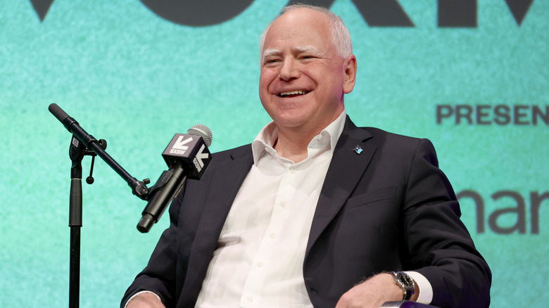 Tim Walz laughing onstage in front of a microphone