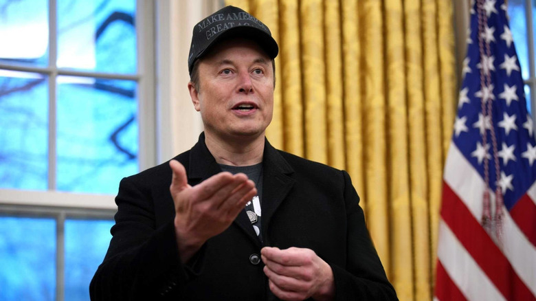 Elon Musk speaking in a black MAGA hat in the Oval Office