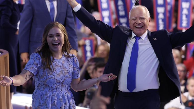 Hope Walz and Tim Walz laughing and raising arms up at the DNC