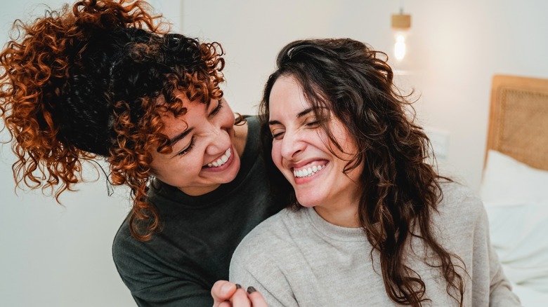 Lesbian/bi women smiling in bed