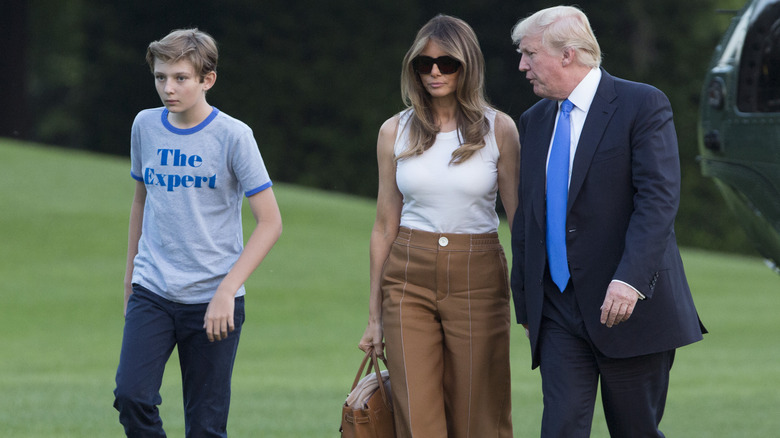 Barron, Melania, and Donald Trump walk on grass