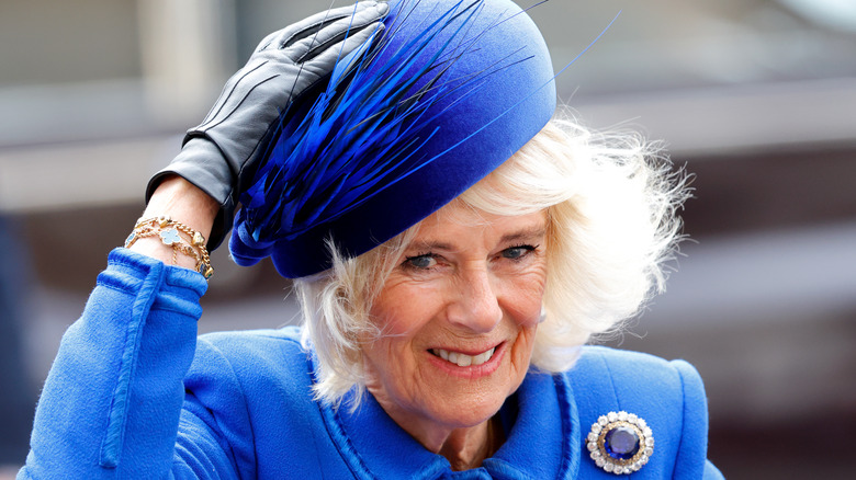 Queen Camilla holding hat from gust of wind