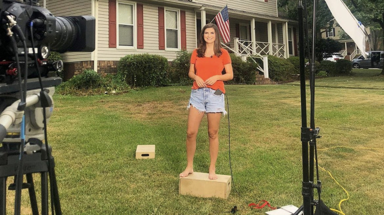 Kaitlan Collins in bright orange top and frayed denim shorts in sister's front yard