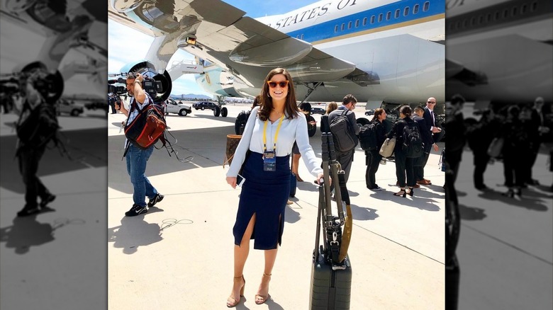 Kaitlan Collins in light blue shirt and navy blue skirt in front of Air Force One