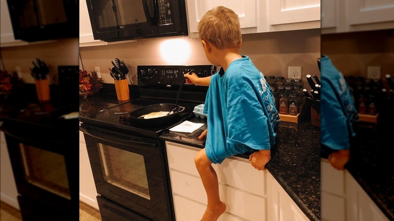 Jill Dillard's son sitting on kitchen counter cooking