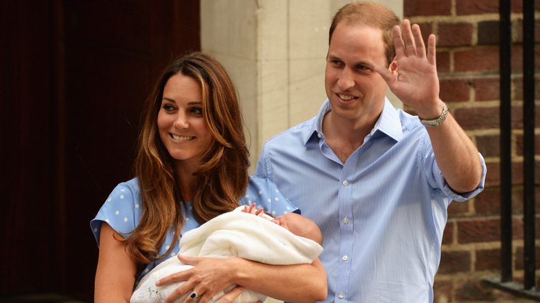 Kate Middleton and Prince William smiling with baby
