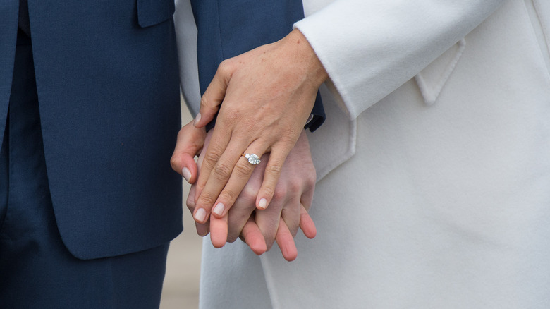 A shot of Harry holding Meghan's hand and showing her engagement ring